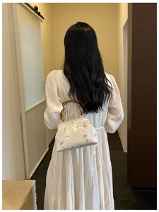 Vista posteriore di donna con borsa a conchiglia ricamata in stile nuovo cinese con manico in bambù