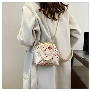Detail of a traditional silk floral handbag featuring a pearl handle and gold chain strap