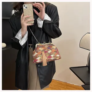 Dettaglio borsa retrò in stile cinese di stoffa con nappa e tracolla a catena dorata.