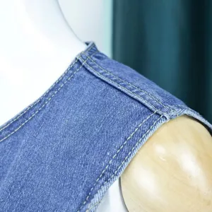 Close-up detail of women's blue denim sleeveless top shoulder and collar stitching.