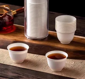 Detail view of disposable tea cups displayed in a clear dispenser on a wooden tray.