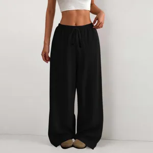 Dettaglio ravvicinato dei pantaloni neri plissettati a gamba larga con coulisse in vita.