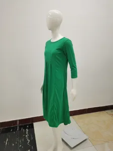 Detalle de vestido midi verde, elegante cuello redondo, mangas 3/4 y dobladillo.