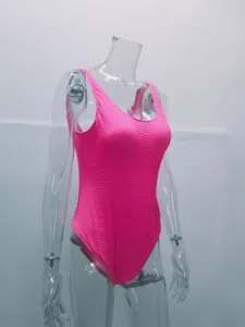 Neon pink crinkled one-piece swimsuit detail view, textured fabric for beach swimwear.