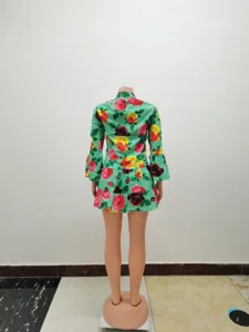 Detail view of a green floral print mini dress with long bell sleeves and tiered hem.