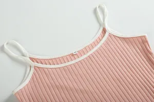 Close-up detail of women pink ribbed knit camisole featuring stylish white contrast trim.
