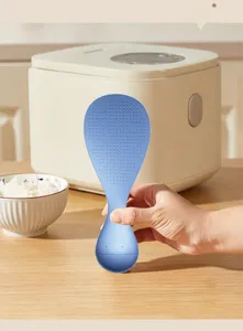 Gros plan détaillé d'une cuillère à riz bleue debout sur une table en bois en cuisine.