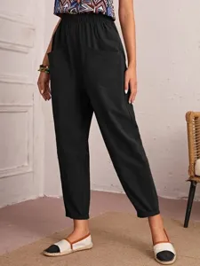 Casual black cropped pants detail showing elastic high waist, side pockets, and slim tapered leg.