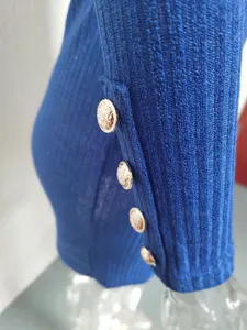 Gros plan détaillé de la manche en tricot côtelé avec des boutons dorés élégants.