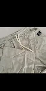 Men's casual trousers detail view showing elastic drawstring waistband and textured fabric.