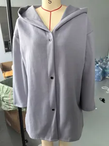 Detailed view of the grey hooded jacket with front snap buttons, showing texture and design.