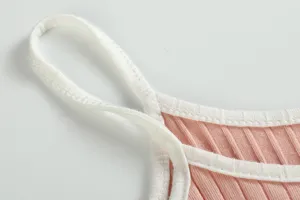 Detailed view of pink ribbed camisole strap and white trim, soft knit fabric texture.