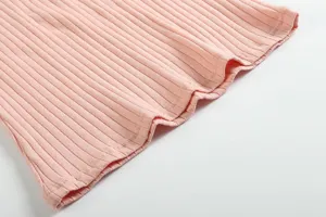 Close-up detail of light pink ribbed knit fabric hem, showing texture and stitching.