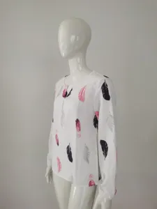 Close-up detail of the white long-sleeve blouse featuring elegant black and pink feather print.