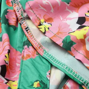 Detailed view of women dress fabric featuring vibrant floral print and neat overlock stitching.