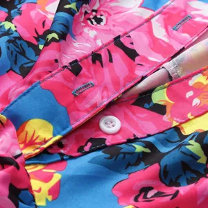 Close-up detail of women's floral print dress featuring colorful pattern and button closure.