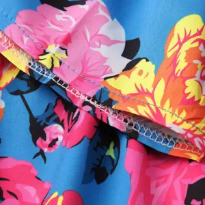 Floral dress detail view, vibrant blue fabric with pink and yellow flower print pattern.
