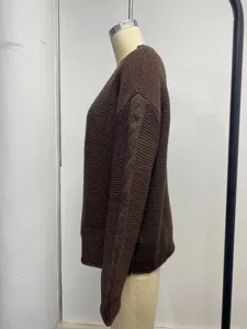 Close-up side view of a dark brown chunky knit sweater showing the cable sleeve detail.