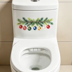 Detalle de una pegatina navideña de pino y bolas de colores en un tanque de inodoro blanco