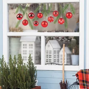 Detail showing festive red ornament and pine branch window decals applied on glass pane