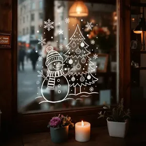 Detailopname van witte handgetekende raamstickers met sneeuwpop en kerstboom op glas