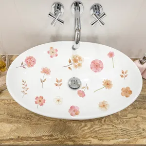 Detail of watercolor Morandi floral stickers applied on a white ceramic sink surface