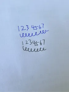 Close-up detail of erasable gel pen writing test with smooth blue and black ink strokes.