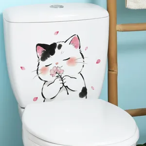 Detail of a cute cartoon cat toilet sticker on a white tank with flower petals.