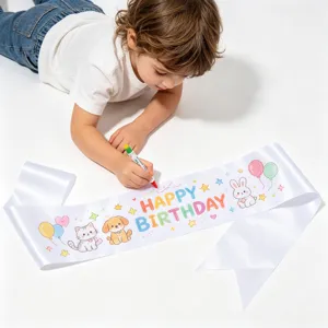 Enfant dessinant sur une écharpe d'anniversaire DIY en satin blanc