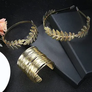 Detailopname van gouden bruidsdiademen met bladeren en een brede draadwikkelarmband.