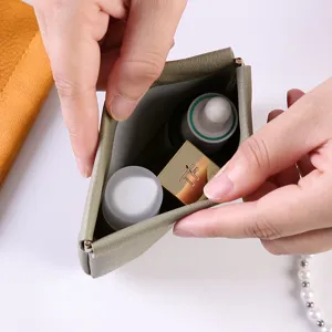 Portable mini green leather kiss-lock cosmetic bag shown open with daily makeup items