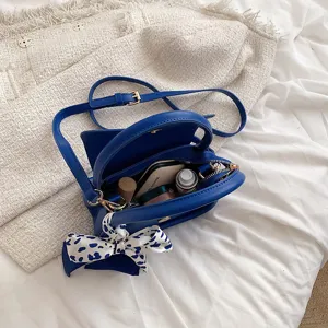 Modische kleine leuchtend blaue Handtasche mit Umhängeriemen und gemustertem Seidenschal