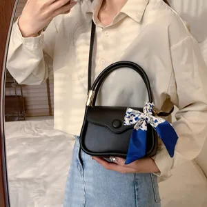 Stilvolle schwarze Satteltasche mit dekorativem blauem Seidenschal und Golddetails.