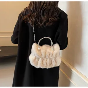 Rear view of a elegant fluffy faux fur handbag with rhinestone handle worn over black coat