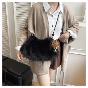 Model trägt eine schwarze Kunstfell-Schultertasche mit einem braunen Plüschtier-Anhänger.