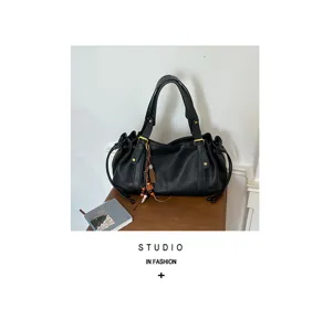 Borsa a secchiello retrò in morbida pelle nera con nappine decorative su tavolo