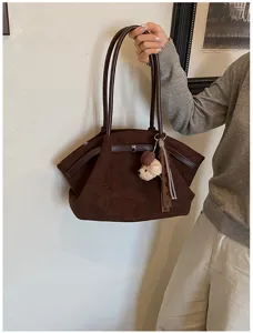 Detailweergave van grote bruine vintage suède tas met schattige beer hanger en lint