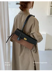 Stylish brown and black quilted baguette bag worn by a model in a minimal studio setting