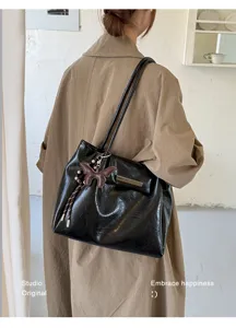Detailansicht einer Vintage-Falten-Tote-Tasche aus schwarzem Leder mit Schmetterlingsanhänger