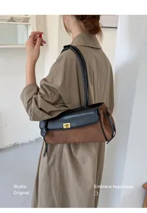 Close-up of brown quilted underarm baguette bag with gold lock closure for women.