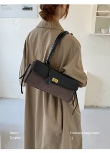 Detail of a brown quilted baguette shoulder bag with black flap and gold lock worn by model.