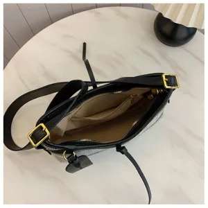 Vista detallada del forro beige y el bolsillo interior con cremallera de un bolso a rayas