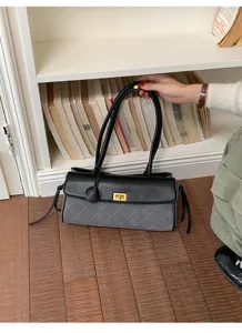 Close-up of a black and grey quilted baguette bag with dual straps and a gold lock on a floor