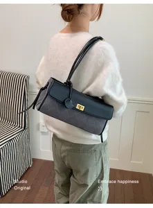 Close-up view of a grey quilted baguette shoulder bag with a black leather flap and metal lock