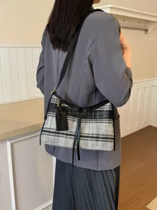 Bolso hobo vintage a rayas blancas y negras lucido por una modelo con un blazer gris