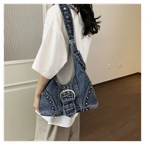 Detailed side view of a vintage washed denim shoulder bag featuring punk rivets and a large buckle