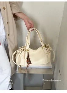 Dettaglio della borsa a secchiello vintage in pelle con coulisse crema e ciondolo nappa