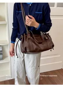 Borsa a secchiello retrò marrone in morbida pelle indossata come borsa a tracolla