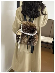 Rear view of a fuzzy fawn-print backpack with white lace trim and teddy bear charm