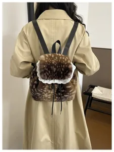 Back view of a furry deer-patterned backpack with delicate white lace trim on a beige coat.